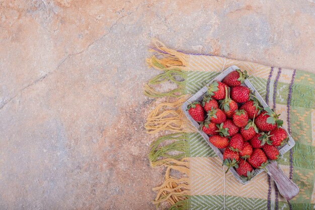 Fraises rouges sur plateau rustique carré.