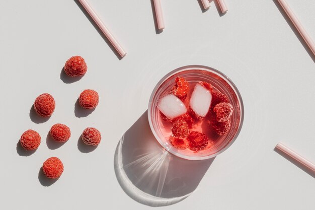 Photo gratuite framboises mûres fraîches et jus de framboise dans un verre et des pailles