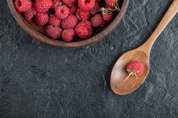 framboises mûres rouges dans un bol en bois sur une table en marbre