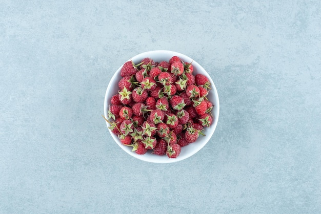 Framboises rouges fraîches dans un bol blanc.