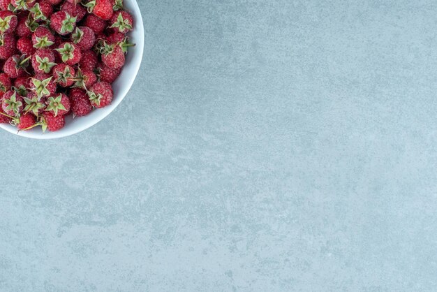 Framboises rouges fraîches dans un bol blanc.