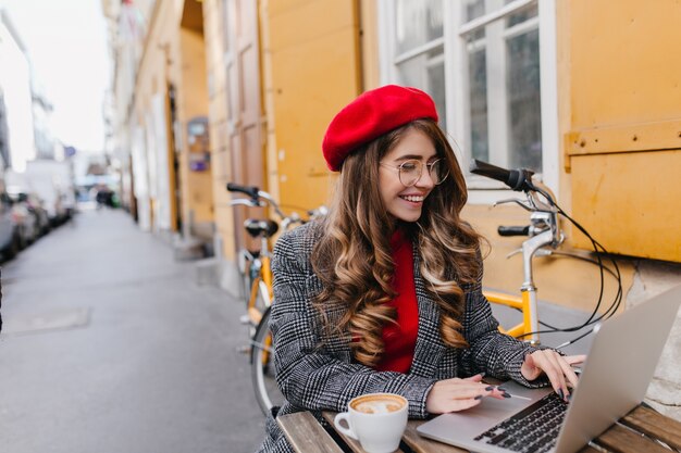 Freelance femme souriante occupée, passer du temps dans un café en plein air