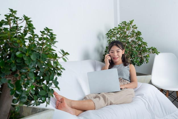 Freelance, travail à domicile - une jeune femme utilise le téléphone lorsqu'elle travaille au salon.