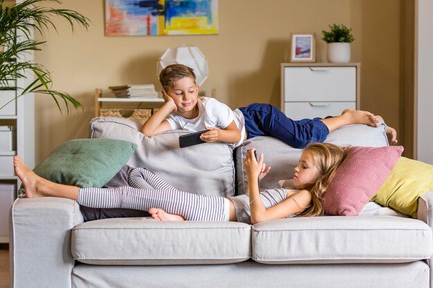 Frère et sœur dans le salon assis sur le canapé