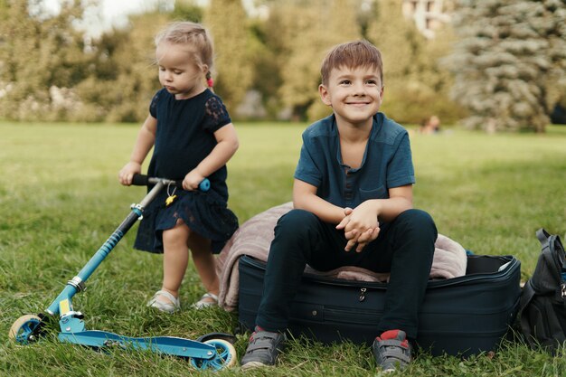 Frère et sœur avec un scooter dans le parc