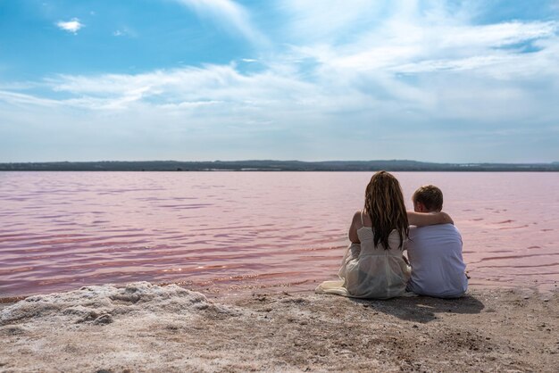 Frères adolescents mignons assis sur une rive du magnifique lac rose