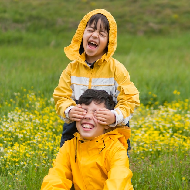 Frères en imperméable jouant dans le parc