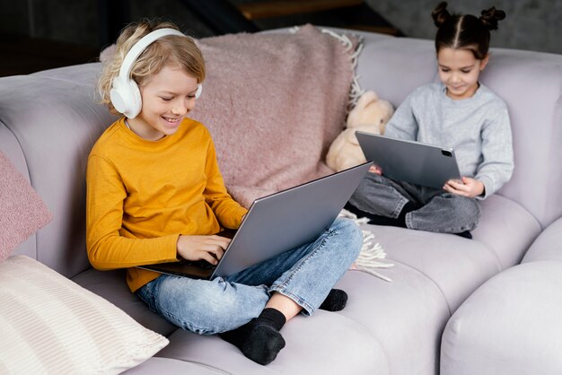 Frères et sœurs sur canapé avec ordinateur portable