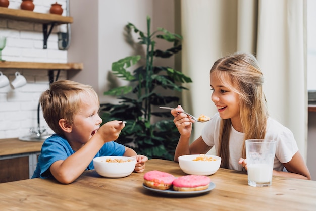 Photo gratuite frères et sœurs mangeant ensemble dans la cuisine