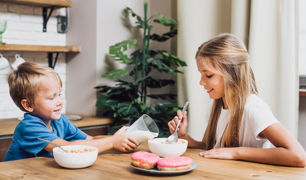 Frères et soeurs vue de face manger ensemble dans la cuisine