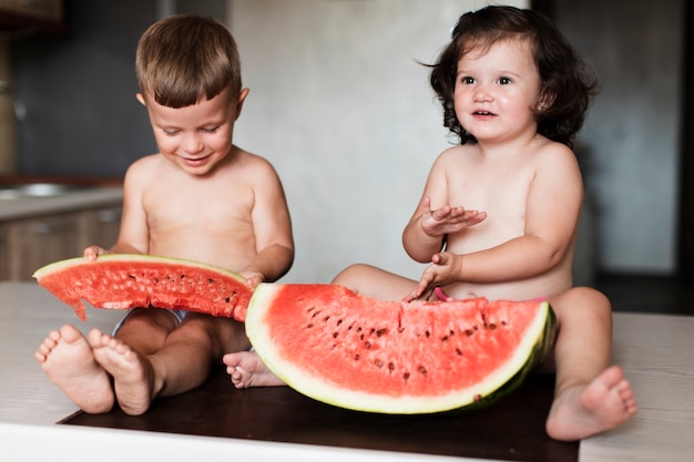 Photo gratuite frères et sœurs vue de face avec des tranches de melon d'eau