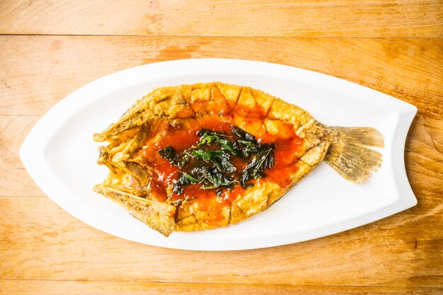 Fried poissons de loup de mer en plaque blanche avec la sauce épicée et sucrée