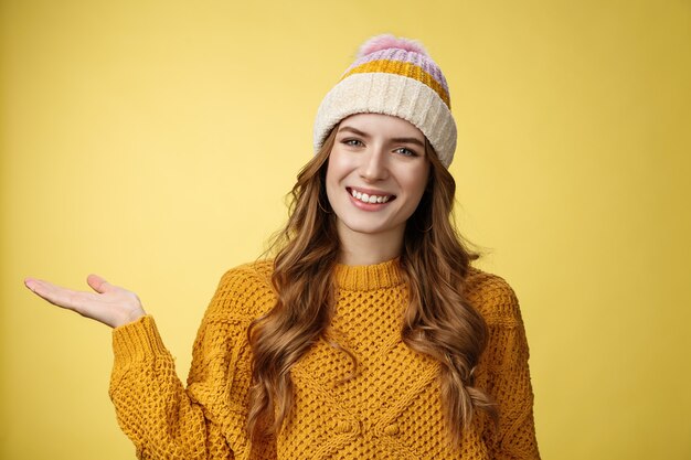 Friendlylooking confiant agréable attirante jeune femme européenne portant un chandail de chapeau d'hiver s'étendent ...