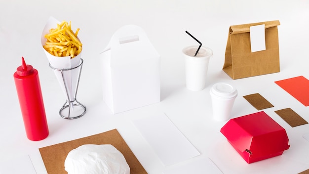 Des frites avec des aliments emballés; bouteille de sauce et tasse d&#39;élimination sur fond blanc