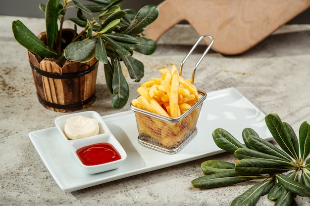 Frites dans un panier servi avec du ketchup et de la mayonnaise