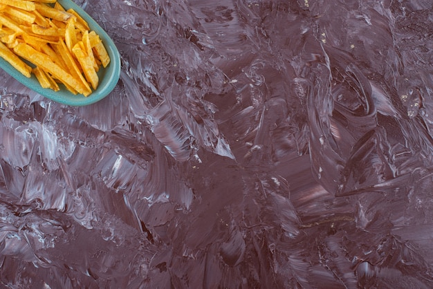 Frites de pommes de terre dans une assiette , sur la table en marbre.