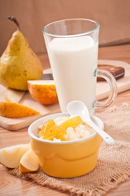 Fromage cottage avec confiture de poire dans un bol et un verre de lait