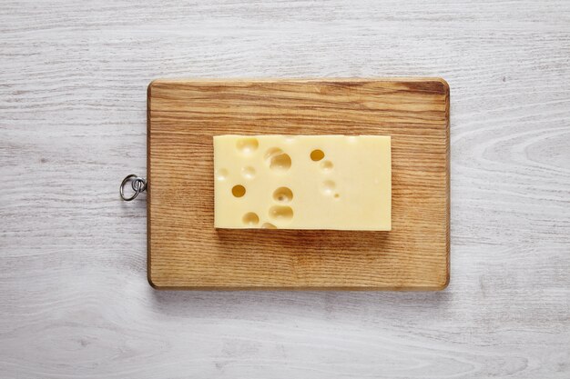 Fromage emmental isolé à bord sur table de ferme brossé blanc