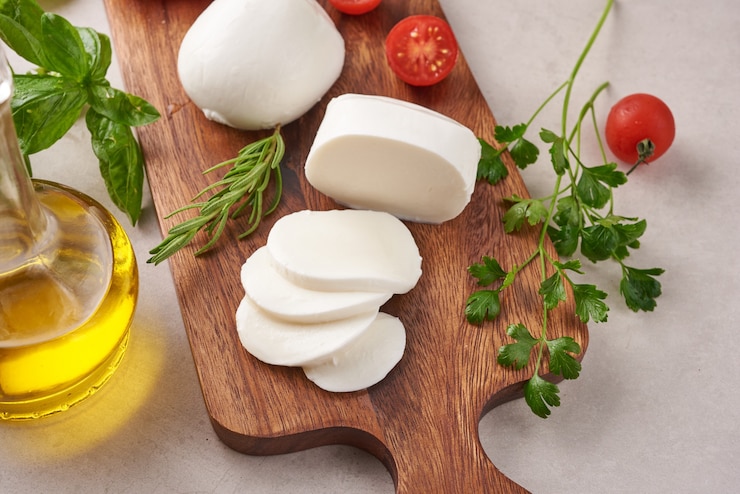 Photo gratuit fromage mozzarella frais, fromages italiens à pâte molle, tomate et basilic, huile d'olives et romarin sur planche de service en bois sur une surface en bois clair. la nourriture saine. vue de dessus. mise à plat.