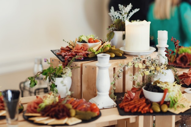 Le fromage en tranches et la viande sont servis sur un plat avec des olives sur des boîtes en bois