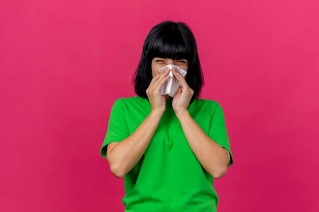 Photo gratuite fronçant les sourcils jeune femme malade à l'avant essuyant le nez avec serviette isolé sur mur rose