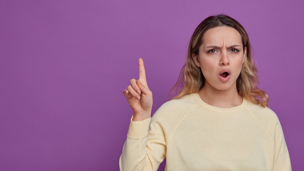 Fronçant les sourcils jeune fille pointant vers le haut