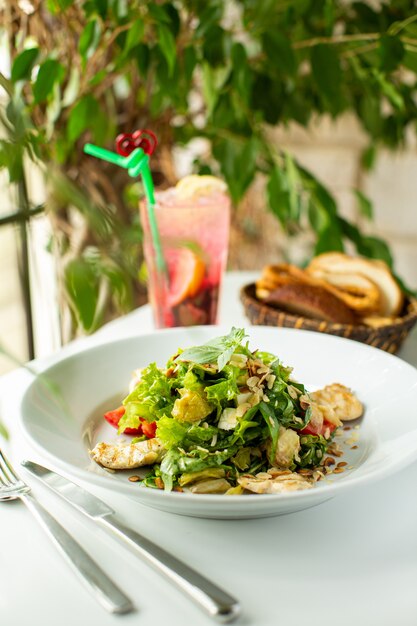 Un front close up view salade fraîche avec des légumes et des tranches de légumes à l'intérieur de la plaque blanche sur le sol blanc