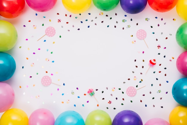 Frontière de ballons colorés avec des confettis et des accessoires sur fond blanc