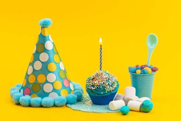 Un frotn view guimauves et bonbons avec gâteau d'anniversaire avec bougie sur bureau jaune, anniversaire couleur bonbon