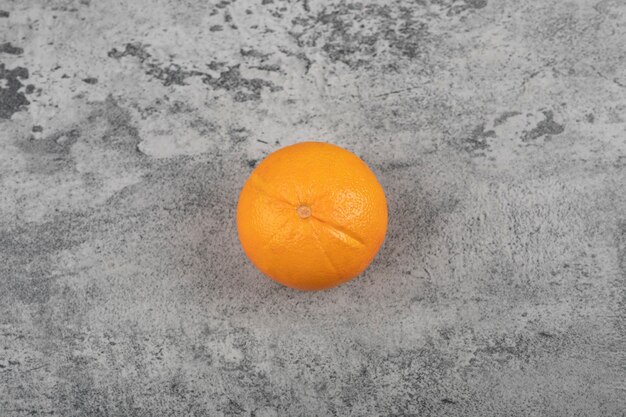 Un fruit orange sain et frais entier sur une table en pierre.