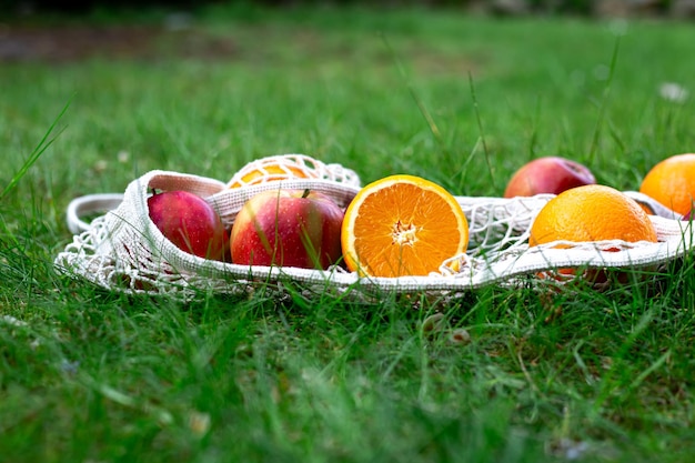 Photo gratuite fruits brillants dans un sac à cordes blanc dans l'herbe