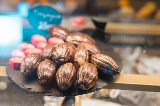 Fruits de cacao en forme de chocolats sur un plateau de roche dans la vitrine
