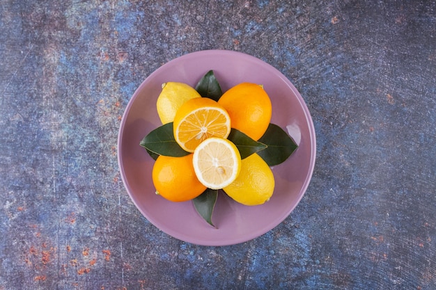 Fruits de citron entiers et tranchés placés sur une pierre.