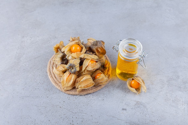 Fruits de cumquat séchés sains avec du miel placé sur une table en pierre.