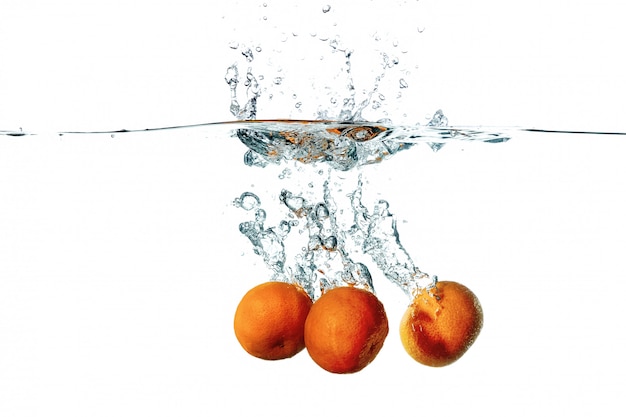 Fruits frais de mandarine tombant dans les éclaboussures d'eau