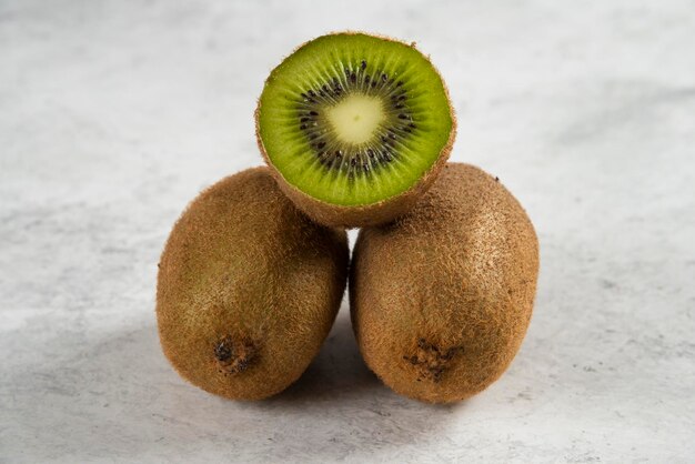 Fruits de kiwi entiers et demi-kiwis sur blanc.