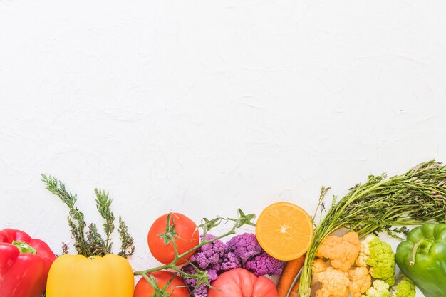 Fruits et légumes colorés sur fond texturé blanc