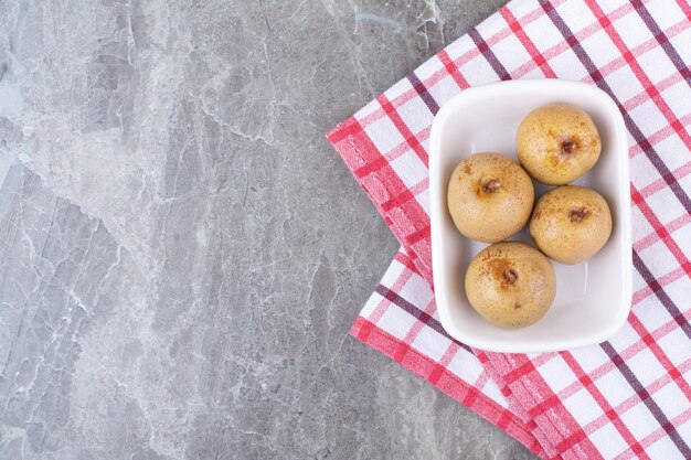 Fruits marinés dans un bol blanc avec nappe.