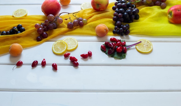 Photo gratuite fruits mélangés sur une écharpe jaune sur une table blanche, vue de coin.