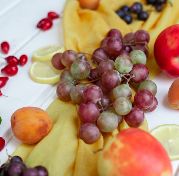 Fruits mélangés sur un ruban jaune sur une table blanche.