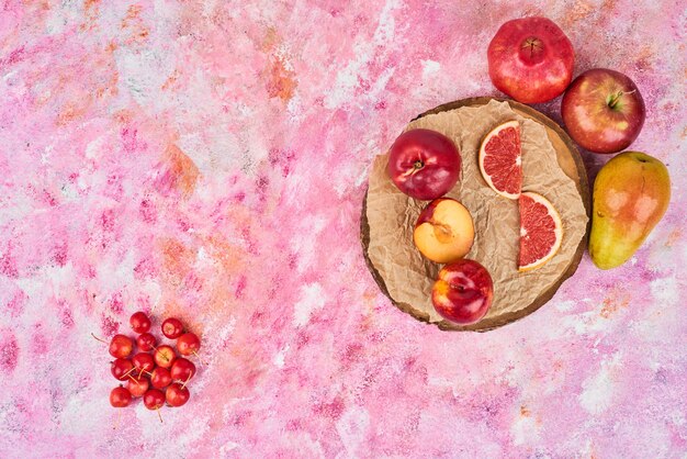 Fruits sur planche de bois rose, vue de dessus.