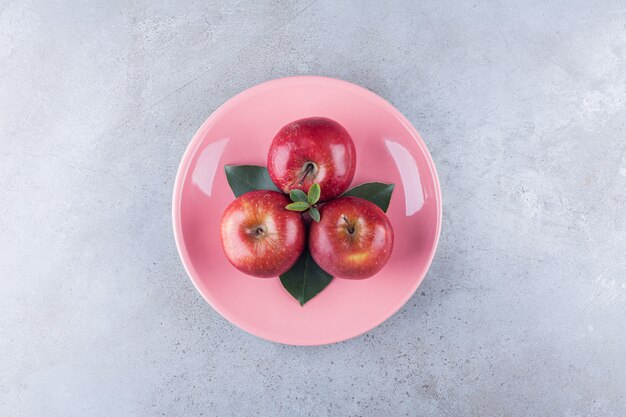 Fruits de pomme mûrs rouges placés sur une table en pierre.