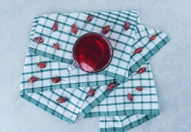 Fruits de rose musquée et thé sur serviette sur marbre.