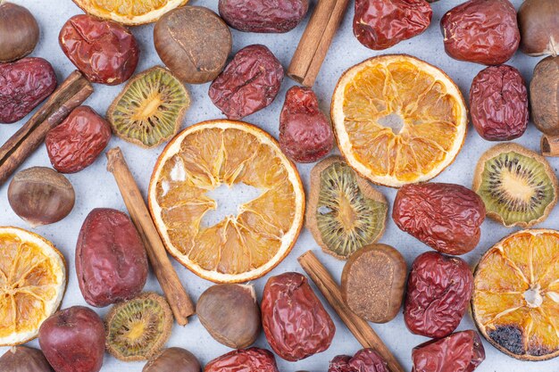 Fruits secs, bâtons de cannelle et châtaigne sur une surface en marbre.