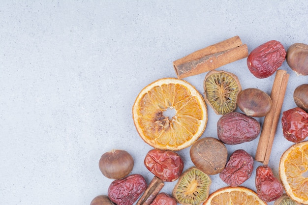 Fruits secs, bâtons de cannelle et châtaignes sur une surface en marbre.