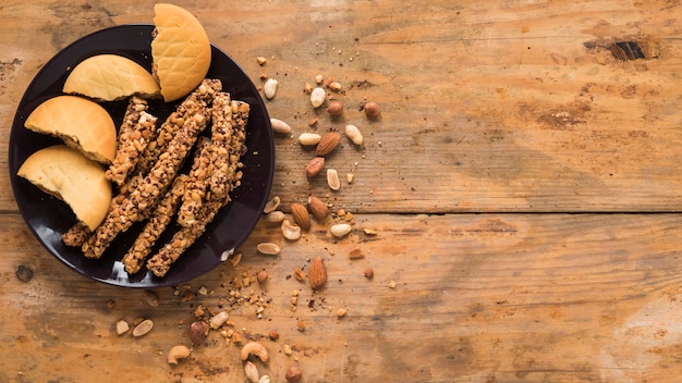 Fruits secs; biscuits et barre granola sur fond texturé en bois