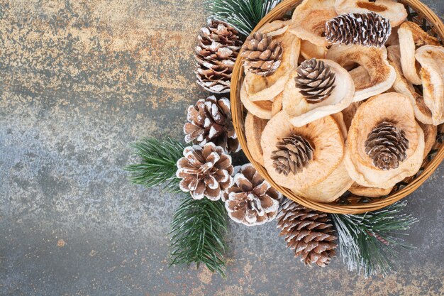 Fruits secs et pommes de pin dans un bol en bois sur fond de marbre.Photo de haute qualité