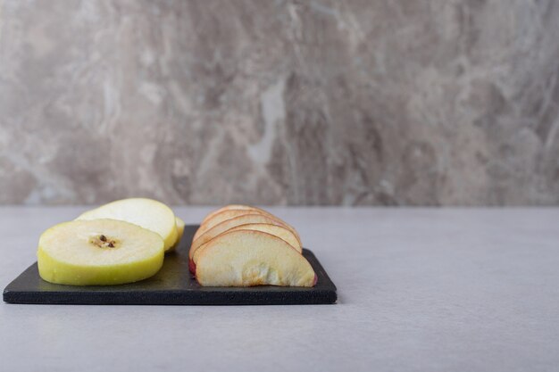Fruits tranchés sur une planche à découper sur une table en marbre.