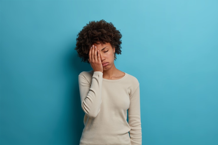 Photo gratuit frustré malheureux jeune femme fatiguée fait la paume du visage, garde les yeux fermés et soupire de fatigue, porte un pull blanc, pose contre un mur bleu, dérangé par quelque chose d'ennuyeux, se sent fatigué