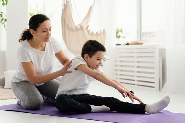 Full shot femme et garçon sur tapis de yoga